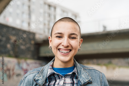 Happy young woman with shaved head smiling in front of camera