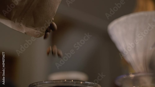 Fresh roasted specialty coffee beans pouring in a grinder by a Barista preparing to grind coffee, making freshly ground coffee photo