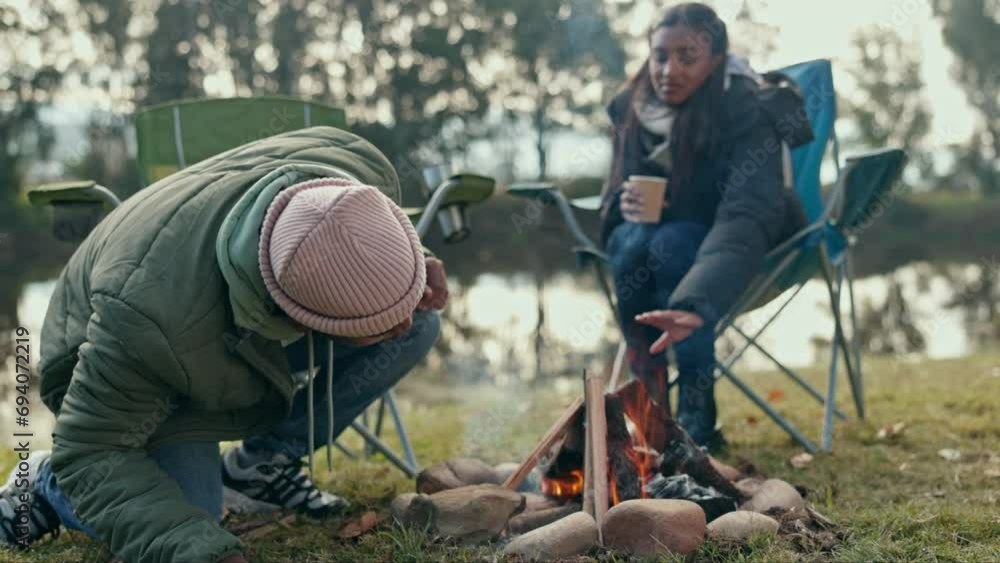 Fire, camping and couple in a forest relax, happy and bond, freedom and travel adventure in nature. Wood, fire and people at camp site with love, coffee and and share exploration experience at lake Fire, camping and couple in a forest relax, happy and bond, freedom and travel adventure in nature. Wood, fire and people at camp site with love, coffee and and share exploration experience at lake