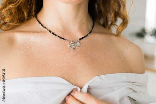 Female with silver pendant heart close-up. Image for e-commerce, online selling, social media, jewelry sale. Handmade jewelry