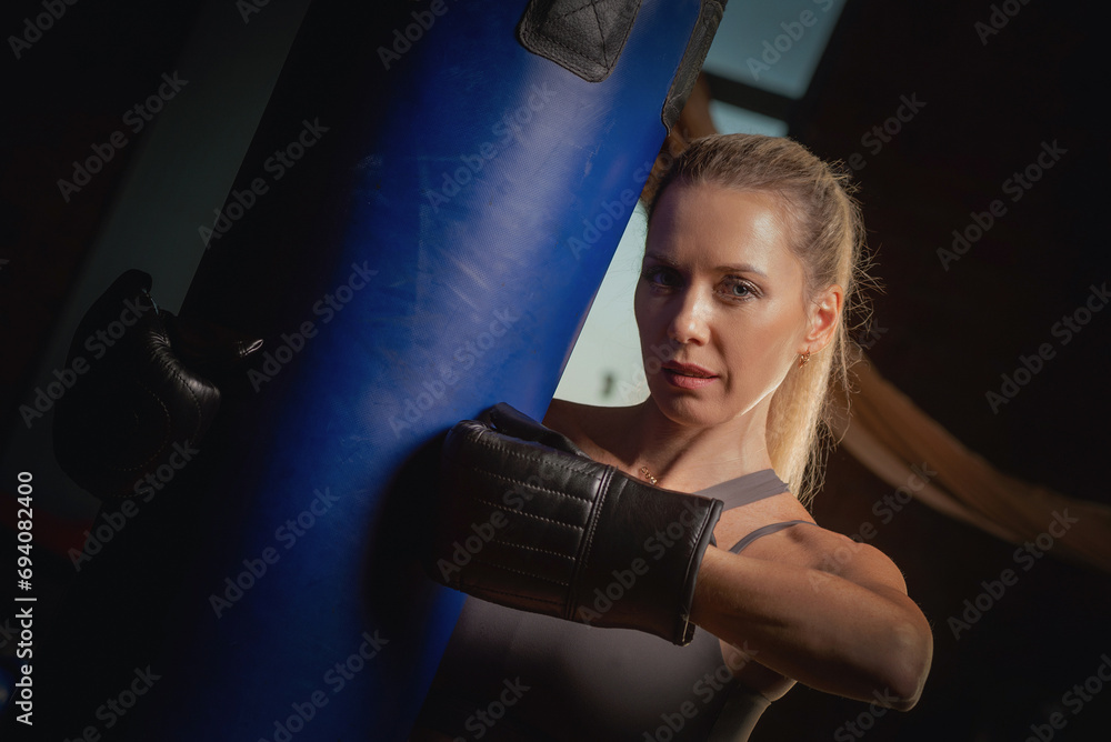 Young woman in the boxing gloves posing in the gym. Boxer woman concept.