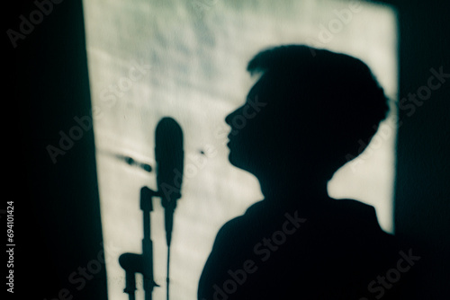 Obraz na plátně Silhouette of a singer rehearsing with their microphone, about to record
