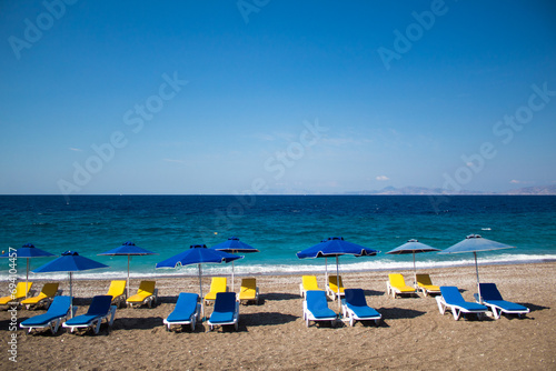 Summer vacation concept: empty beach chairs and umbrellas, blue sea in the background. Free copy space