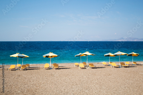 Summer and holiday concept: beach chairs and umbrellas, no people, empty beach, beautiful blue sea