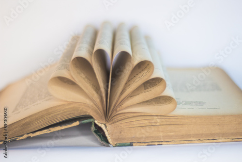 Old, open book arranged in a decorative form, white background, selective focus
