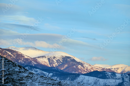 Cold snowy mountain landscape at sunset. Panoramic view of snowy mountain peaks and slopes of North Chuyskiy ridge at sunset. Russia, Siberia, Altai mountains.  photo