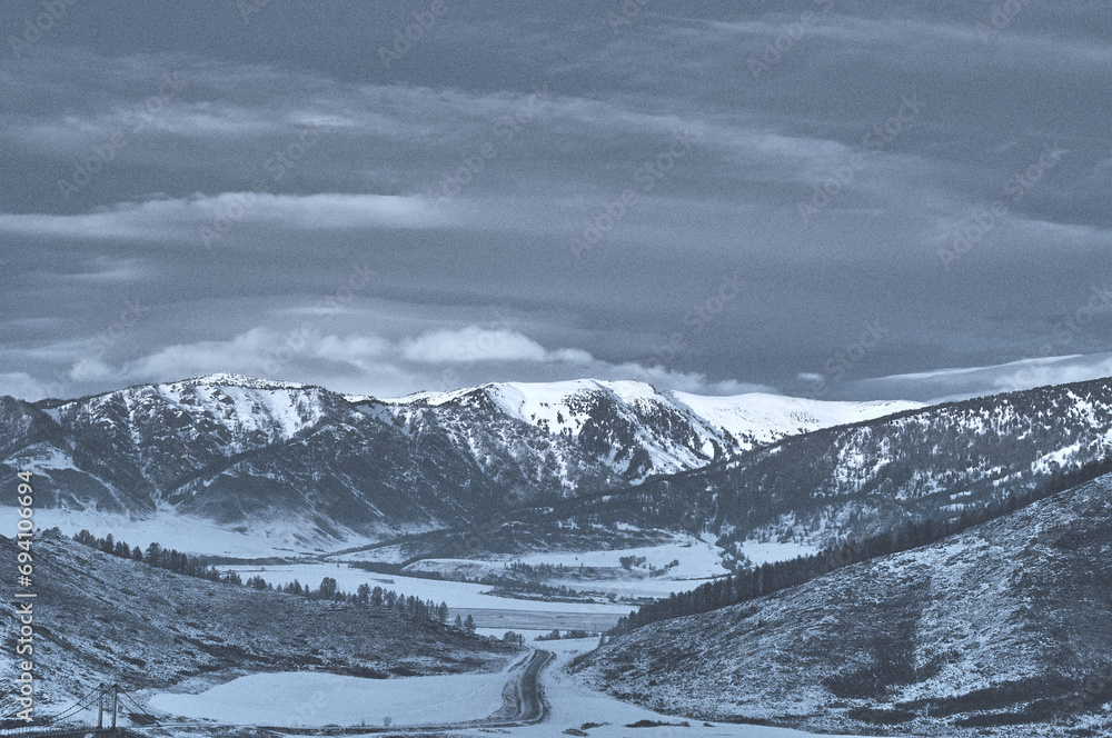 Fototapeta premium Cold snowy mountain landscape at sunset. Panoramic view of snowy mountain peaks and slopes of North Chuyskiy ridge at sunset. Russia, Siberia, Altai mountains.