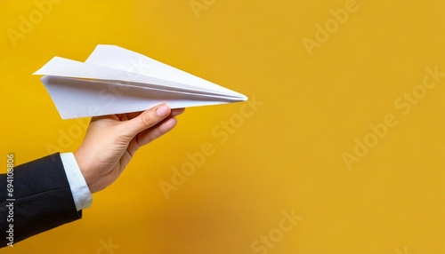 hand holding paper plane over yellow background panoramic mock up image photo