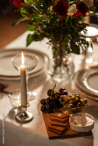 holidays  dinner party and celebration concept - close up of festive table serving with food  flowers and burning candles at home