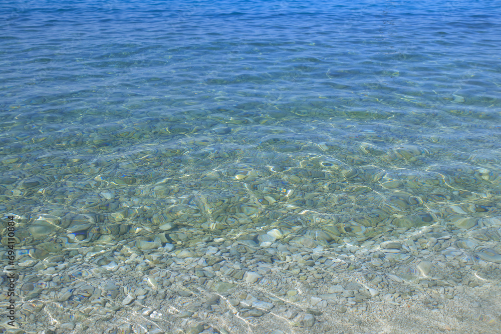 water waves with stones on a bottom. Summer vacation. Abstract water surface. Water waves background. Water waves with shining pattern texture background. Sea water waves with stones on a bottom. Summer vacation. Abstract water surface. Water waves background. Water waves with shining pattern texture background. Sea