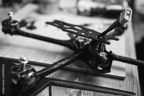 black and white photo, Frame, FPV racing drone frame, assembly, soldering, for the armed forces of Ukraine, installed with tools on the desktop, close-up view photo