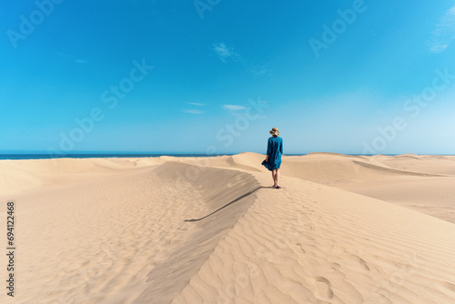 A woman hikes through sand dunes of Maspalomas, Gran Canaria, Spain