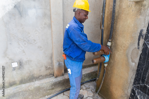 An African blue collar worker preparing to replace dirty rusty water filters photo