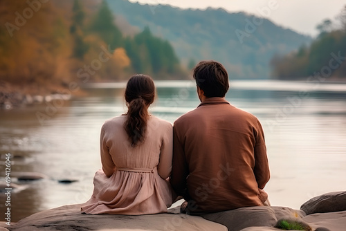 Couple against river background, backs touching, symbolizing relationship cooling. Beautiful view, evoking emotional depth and contemplation. Couple on the big river background, view from back