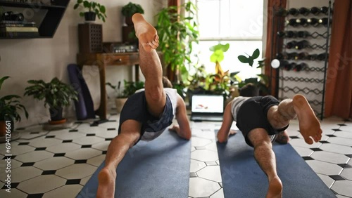 Man, friends and laptop in yoga for stretching, online class or exercise in living room together at home. Rear view of male person, people or yogi in body warm up, workout or training on mat at house photo