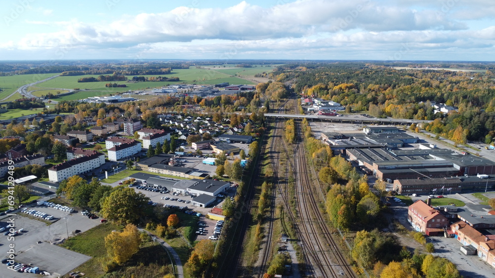 Small Cozy Northern European Town Split by Railroad Tracks with Green Fields on one side and an Autumn Forest on the other