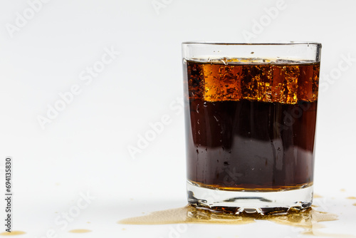Carbonated drink with bubbles and ice in a glass on a white background, delicious drink