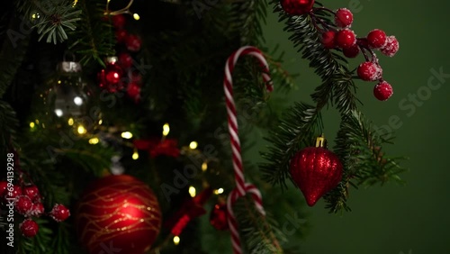 Close-up of female hand in red sweater decorating Christmas tree with striped candies and other toys. Christmas and New Year concept, beautiful holiday video, background. Holiday tree.