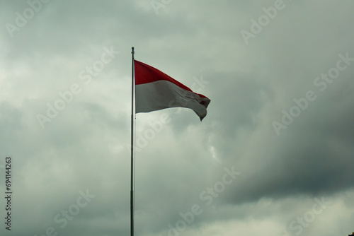 The Indonesian flag, "bendera merah putih", flutters in the gray sky. The concept of sadness or disaster in Indonesia. 