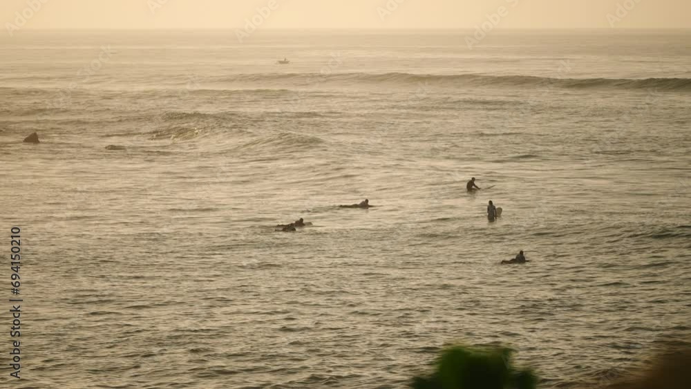 Surfers paddle out in ocean waves at golden hour. Adventure seekers surf, engage in water sports activity. Wave riders awaiting swell, perform aquatic sport. Outdoor lifestyle, sunset surfing. Surfers paddle out in ocean waves at golden hour. Adventure seekers surf, engage in water sports activity. Wave riders awaiting swell, perform aquatic sport. Outdoor lifestyle, sunset surfing.