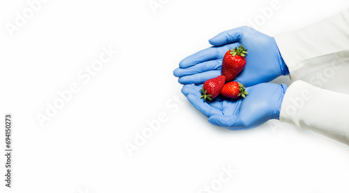 A man in medical gloves holds a red strawberry, protection against infection