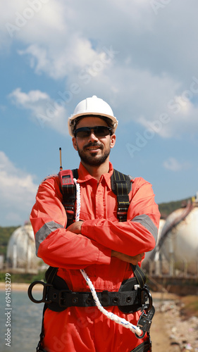 Portrait of smart engineer with safety uniform and harness equipment at the petrochemical site 