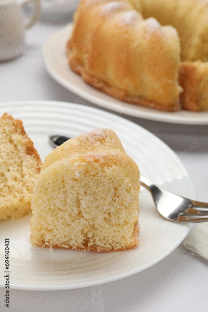 Pieces of delicious sponge cake and fork on white table, closeup Pieces of delicious sponge cake and fork on white table, closeup