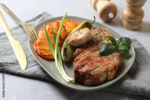 Delicious grilled meat and vegetables served on light grey table  closeup