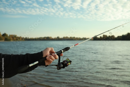 Fisherman with rod fishing at riverside, closeup