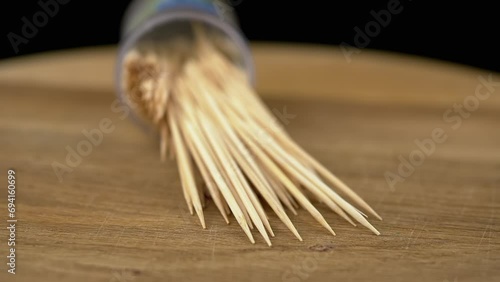 Scattered Toothpicks Rotate on a Wooden Background. Close up. A set of bamboo wooden toothpicks in a plastic cup. Home oral care after meals. Teeth cleaning. Blurred motion. Dentistry concept. Loop. photo