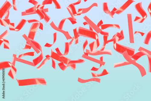 Bright red confetti falling on gradient light blue background