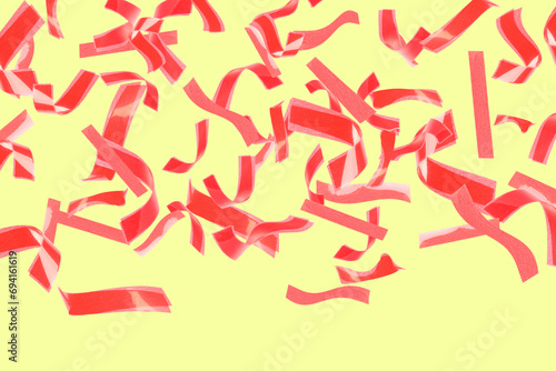 Bright red confetti falling on light yellow background
