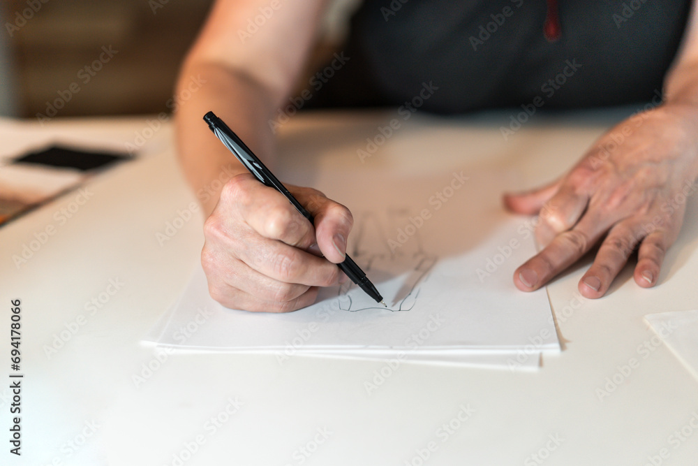 Close-up of a fashion desinger drawing with a pencil. Close-up of a fashion desinger drawing with a pencil.