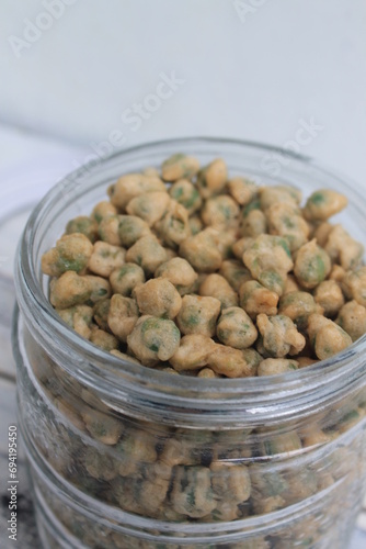 Indonesian snack called flour fried peas (kacang polong) in a jar on the table photo