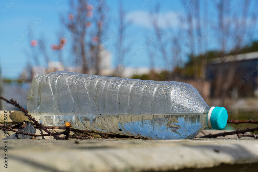 Fototapeta premium Littered plastic water bottle with blue cap lying outdoors. Environmental pollution.