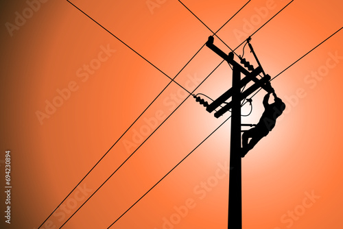 Silhouette of power lineman closing a single phase transformer on energized high-voltage electric power lines. photo