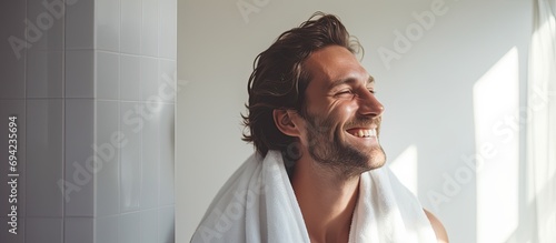 A rejuvenated man dries his hair with a towel after a calming shower, smiling as he takes care of himself in a studio. photo