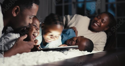 Happy, night and a black family with a tablet on the bed for tickling, playful and laughing at a show. Home, relax and African parents with children, fun and technology in the dark for a cartoon photo