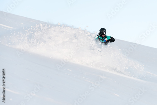 One-armed male skier descends a snowy slope and the snow flies in different directions