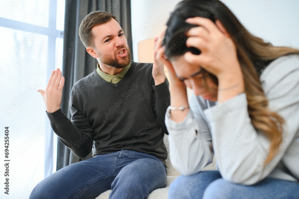 Irritated husband is shouting at his wife with violence. Woman is covering her face with fear Irritated husband is shouting at his wife with violence. Woman is covering her face with fear