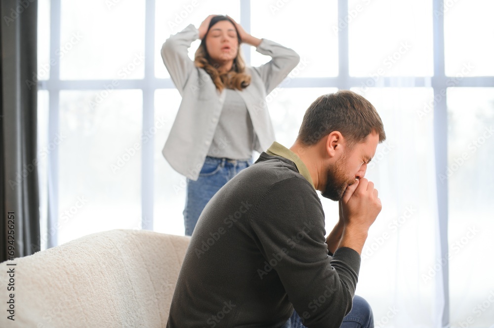 Family quarrel, man and woman sitting on sofa at home. angry woman yells at her husband