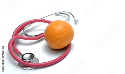 Pomarańcza leży obok stetoskopu na białym tle 