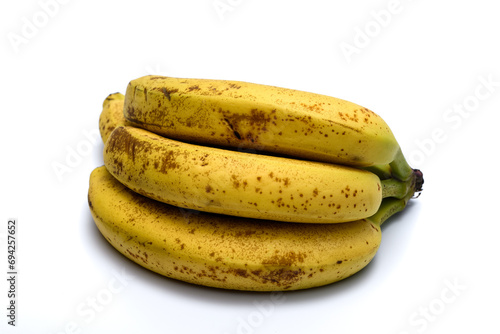 Dojrzałe banany w skórce leżą izolowane na białym tle