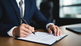 Portrait of smiling businessman sitting at table in office and signing contract