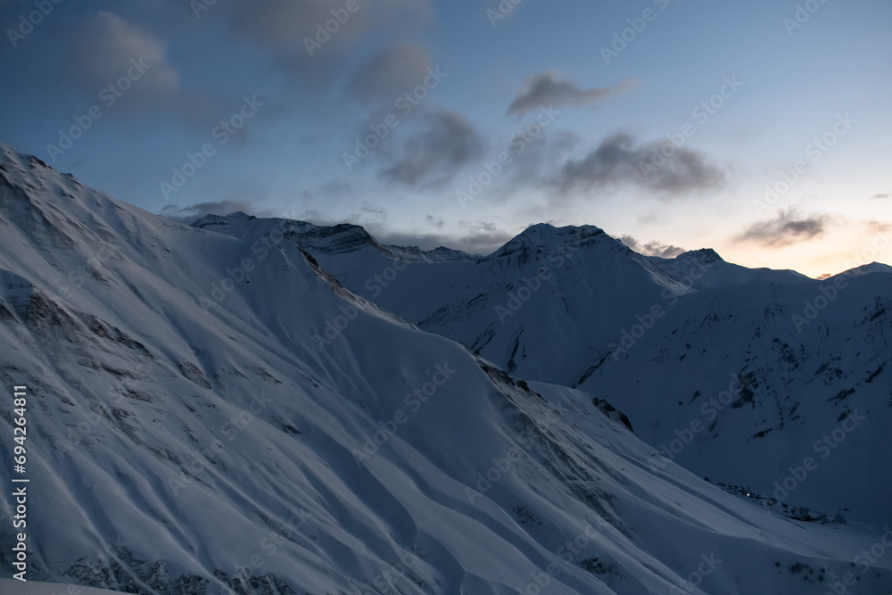 Several snowy slopes on the background of a dark sky