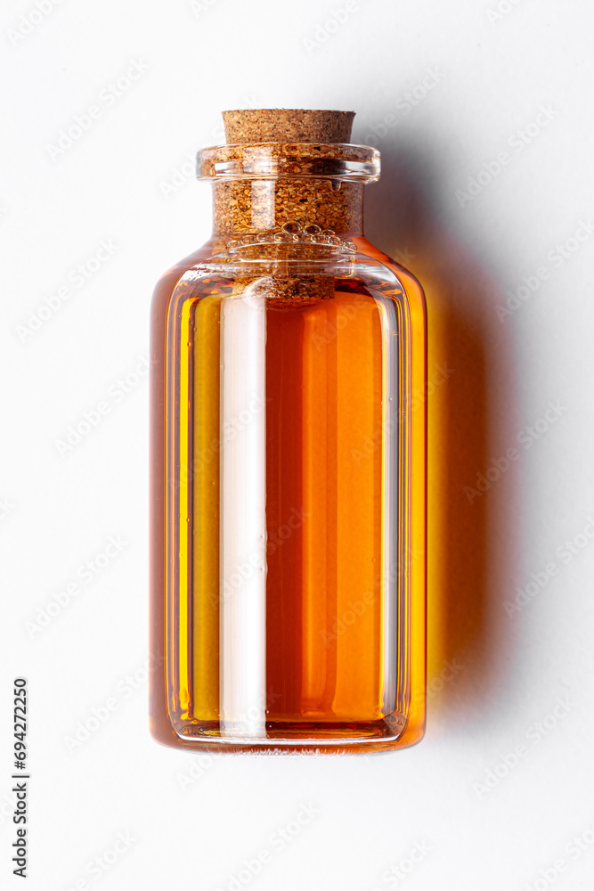 Top-down view of a round glass bottle containing dark orange color essential oil for cosmetics and natural medicine. Top-down view of a round glass bottle containing dark orange color essential oil for cosmetics and natural medicine.