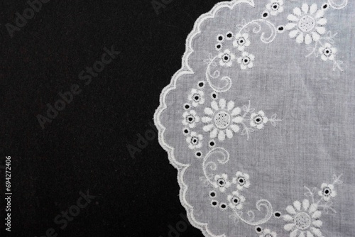 Vintage handmade white knitted napkin isolated on a black background.