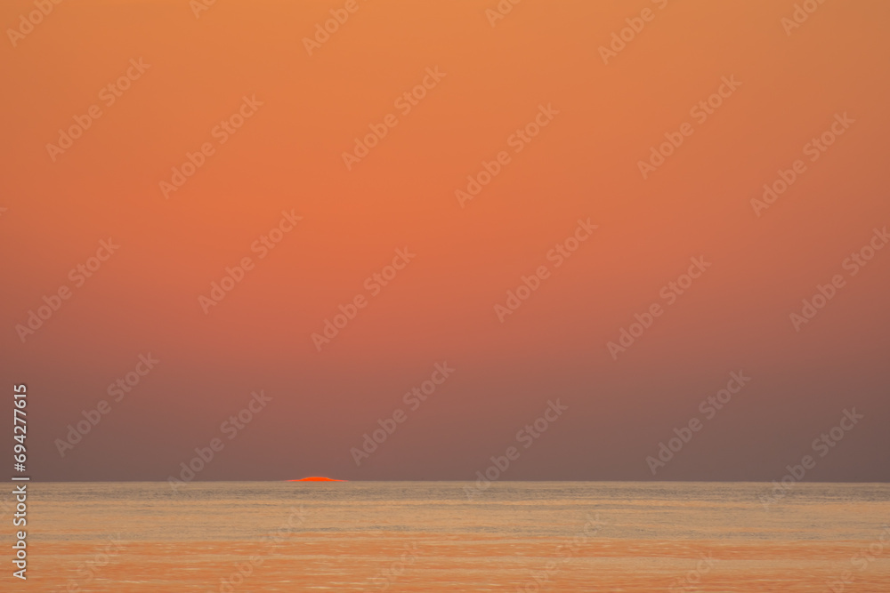 orange red sky one second after sunrise with sun at the horizon from the red sea