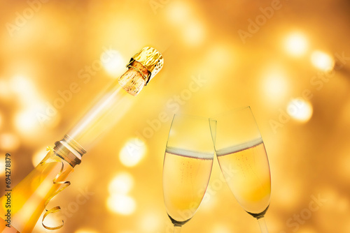 Sektgläser und Flasche vor Verschwommenen Geldenen Lichtern mit Bokeh-Effekt