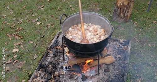 Preparation of delicious unhealthy fried pork greaves in a cauldron on the open fire. Delicious fried pork greaves in the pan traditional Romanian Christmas dish. Crispy deep fried photo